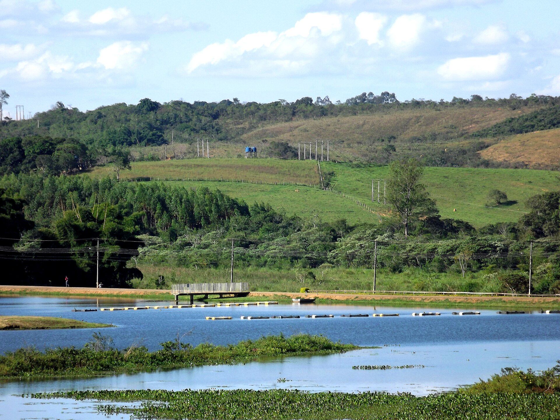 Lago com tanques-rede para criação de tilápia entre pastagens e colinas